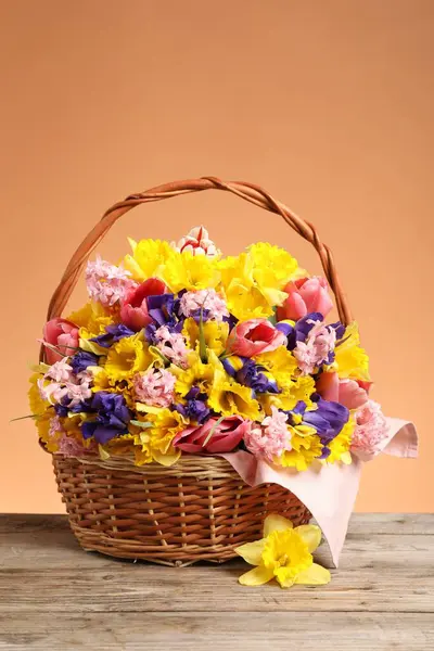 Tahta masada mercan zemin üzerinde güzel çiçeklerle dolu bir sepet.