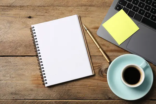 Kalemli defter, yapışkan not, dizüstü bilgisayar ve kahve ahşap masada, düz yatıyordu.