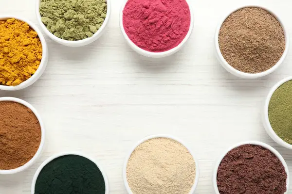 Beyaz ahşap masadaki farklı süper yiyecek tozlarının çerçevesi düz. Metin için boşluk