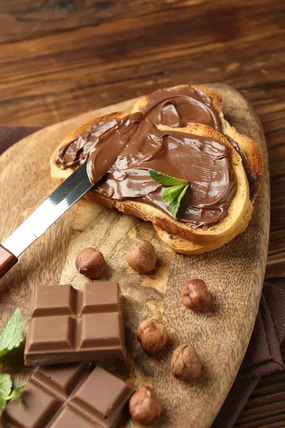 Lezzetli çikolatalı tostlar, parçalar, nane ve fındıklar ahşap masada, yakın plan.