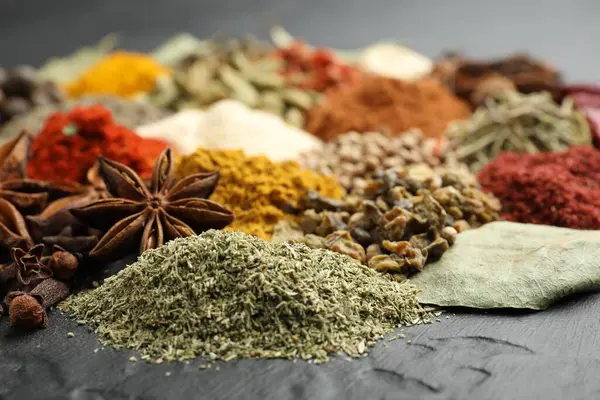 Gri masada farklı aromatik baharatlar, yakın plan.