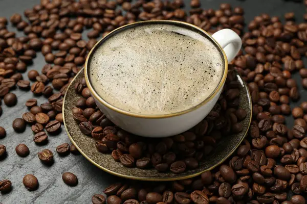 Kahve fincanda, fasulye siyah masada, yakın plan.