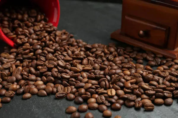 Siyah masada kahve çekirdekleri ve öğütücü, yakın plan.