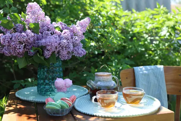 Vazoda güzel leylak çiçekleri, bahçedeki ahşap masada tatlı ve çay.