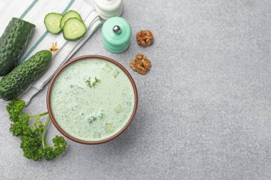 Lezzetli salatalık çorbası ve açık gri masadaki malzemeler. Metin için boşluk