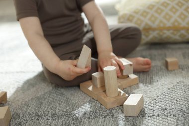 Evdeki ahşap yapı taşlarıyla oynayan sevimli küçük çocuk, yakın plan.