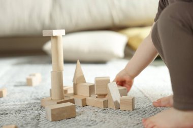 Evdeki ahşap yapı taşlarıyla oynayan sevimli küçük çocuk, yakın plan.