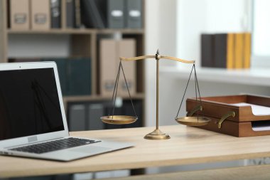 Ofisteki ahşap masada dizüstü bilgisayarı ve terazisi olan yargıcın iş yeri.