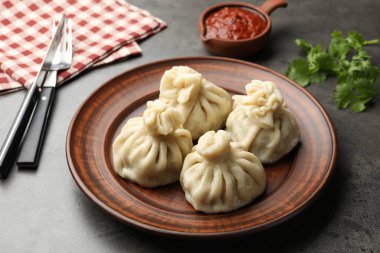 Gri masadaki sosla servis edilen lezzetli khinkali, yakın plan.