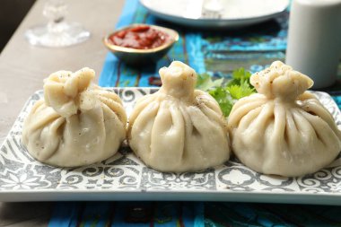 Lezzetli pişirilmiş khinkali. Gri masadaki sosla servis ediliyor. Yakın plan.