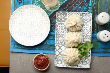 Gri masada soslu kişniş ve kişniş ile servis edilen nefis khinkali.