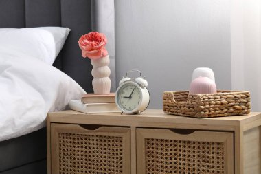 Yatağın yanında alarm saati ve dekorasyonu olan komodinin yanında.