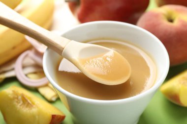 Bebek maması. Yeşil arka planda kaşığı olan lezzetli püreyi yakın plan çekiyoruz.