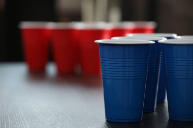 Bira pong oyunu. İçkileri ahşap masaya konmuş plastik bardaklar, yakın plan. Metin için boşluk