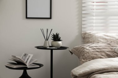 Yatak odasında güzel çarşaflar, yuva masaları ve dekorla rahat bir yatak.