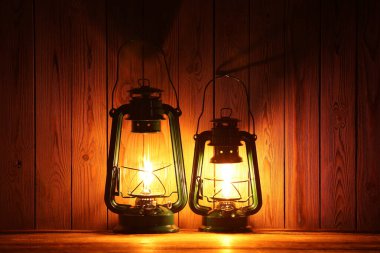 Ahşap masada iki eski gaz lambası.