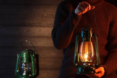 Ahşap duvarın yanında eski tip gaz lambası tutan adam, yakın plan. Metin için boşluk