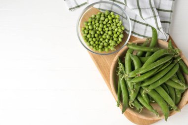 Taze taze bezelyeler beyaz ahşap masada, düz yerde. Metin için boşluk