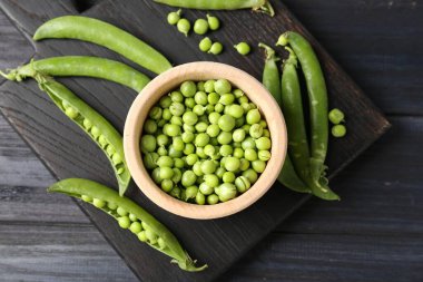 Taze taze bezelyeler siyah ahşap masada, düz yatıyordu.