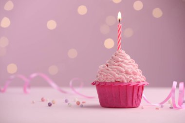 Masanın üzerinde, pembe arka planda, bulanık ışıklarla yanan mum. Metin için boşluk