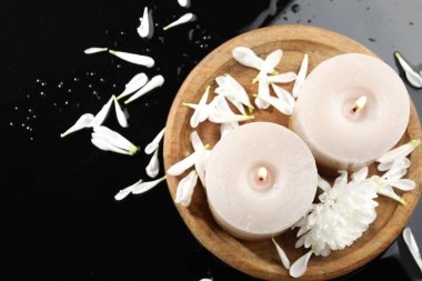 Yanan mumlar ve siyah masada güzel çiçekler, düz uzanmış