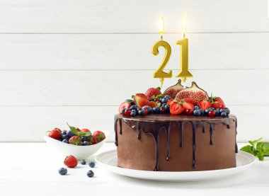 Meyveli lezzetli çikolatalı pasta ve yanan numaralar beyaz masada mumlar, mesaj için yer. 21. yaş günü veya başka özel bir gün.