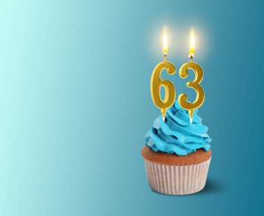 Açık mavi arkaplanda yanan mumlar, yazı için yer olan leziz bir kek. 63. yaş günü veya diğer özel günler