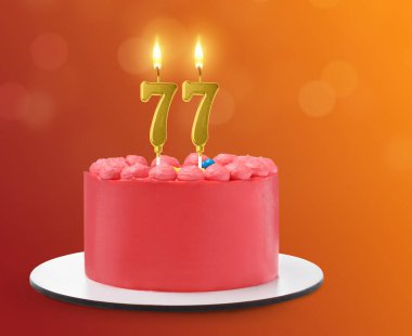 Renk gradyan arka planında mumlar şeklinde yanan lezzetli bir pasta. 77. yaş günü veya diğer özel günler