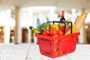 Süpermarketteki ahşap masada alışveriş sepeti dolusu kırmızı alışveriş. Metin için boşluk