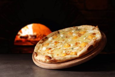 Gri masada fırına karşı nefis sıcak peynirli pizza.