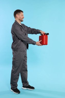 Açık mavi arka planda plastik kutu tutan adam.