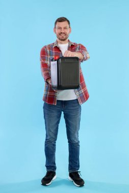 Açık mavi arka planda plastik kutu tutan adam.