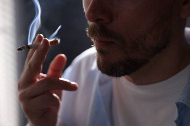 Arka planda sigara içen adam, yakın plan.