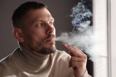 Odada sigara içen bir adam var.