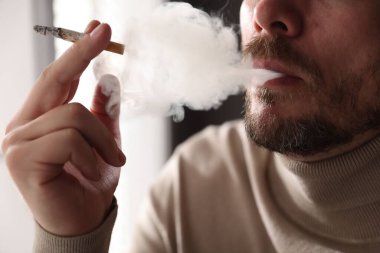 Arka planda sigara içen adam, yakın plan.