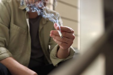 Arka planda sigara içen adam, yakın plan.