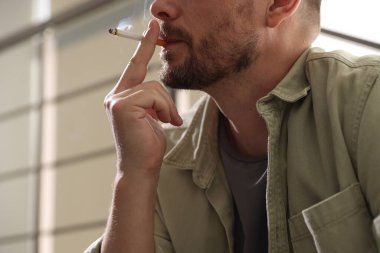 Arka planda sigara içen adam, yakın plan.