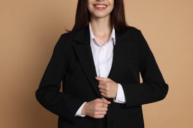 Bej arka planda takım elbiseli kadın, yakın plan.