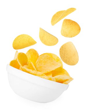 Lezzetli patates cipsleri beyaz arka planda kaseye düşüyor.