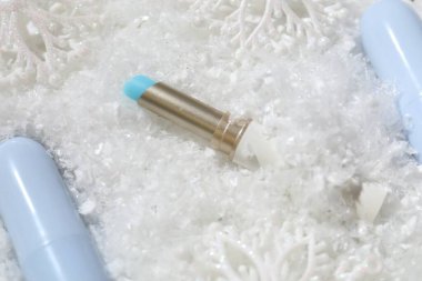 Nemlendirici dudak kremleri ve yapay kar üzerine Noel dekoru, yakın plan. Kış bakımı