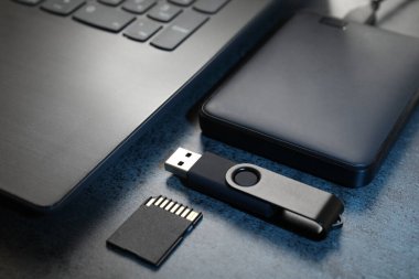 SD hafıza kartı, USB flash disk, sabit disk ve koyu gri masadaki laptop, yakın plan.