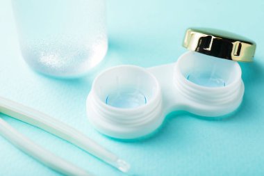 Turkuaz arka planda kontak lensler ve cımbızlar, yakın plan