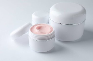 Beyaz arka planda nemlendirici vücut kremi kavanozları, yakın plan.