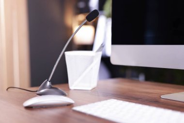 Kapalı alandaki ahşap masada mikrofon ve bilgisayar.