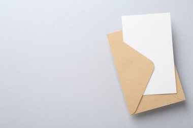 Açık gri arka planda boş davetiye ve zarf, üst manzara. Metin için boşluk