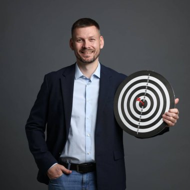 Hedef alınıyor. Dart tahtası ve gri arka planda oku olan bir adam.