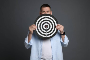 Hedef alınıyor. Gri arka planda dart tahtası olan adam.