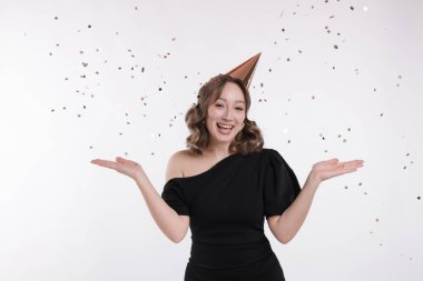 Doğum günü kutlaması. Parti konisi ve beyaz arka planda konfeti olan bir kadın.