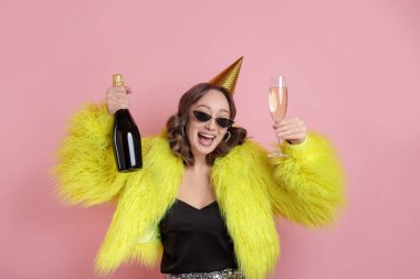 Doğum günü kutlaması. Pembe arka planda köpüklü şarabı olan kadın.