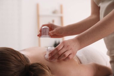 Terapist, kaplıca salonundaki hastaya kupa tedavisi uyguluyor.